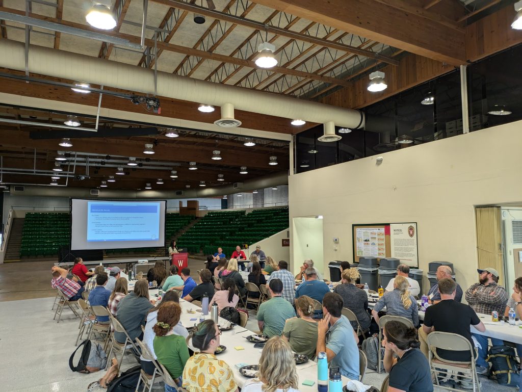 People sitting in a barn watching a soil health presentation